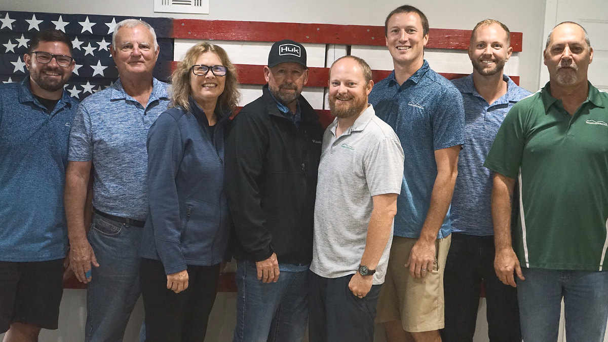 The Triumph Construction team standing together in front of an American flag mural, smiling at the camera