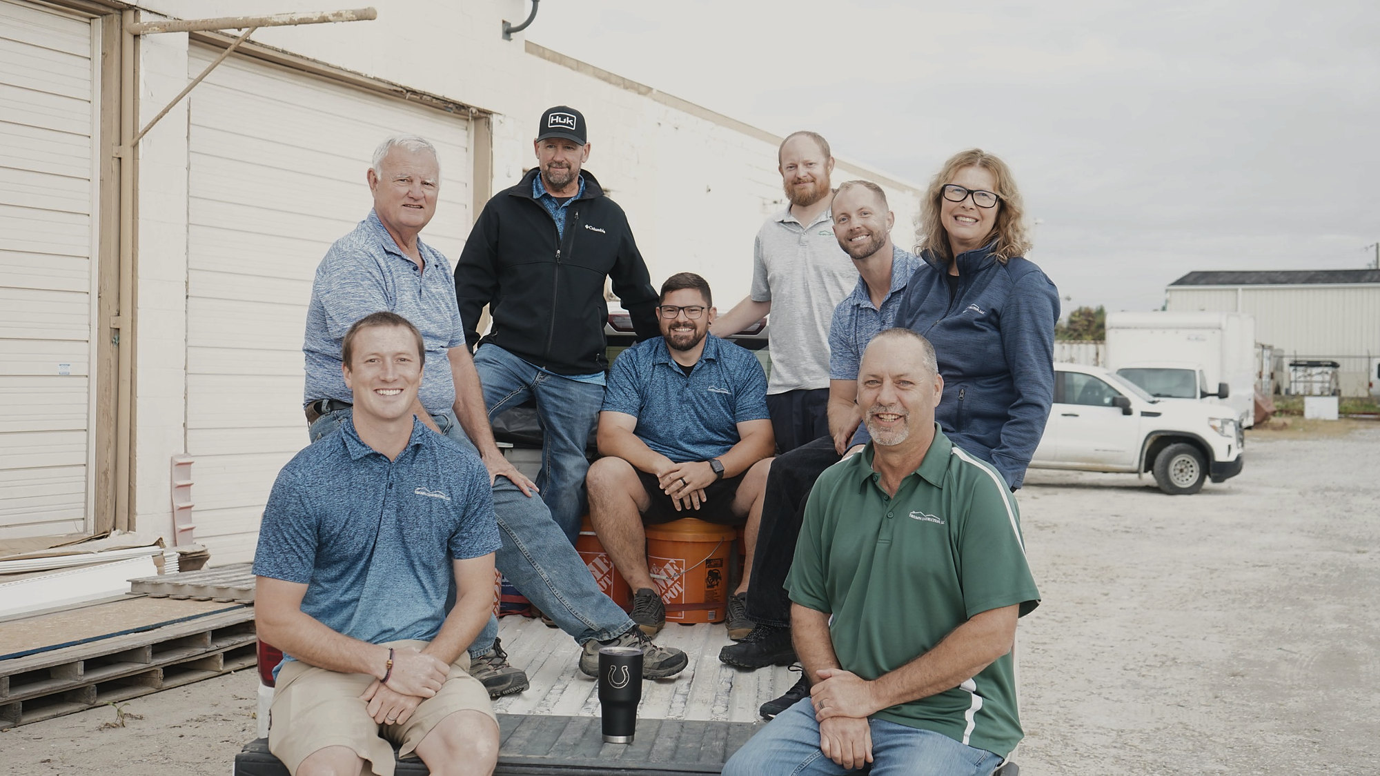 The Triumph Construction team gathered around a work truck outside the shop